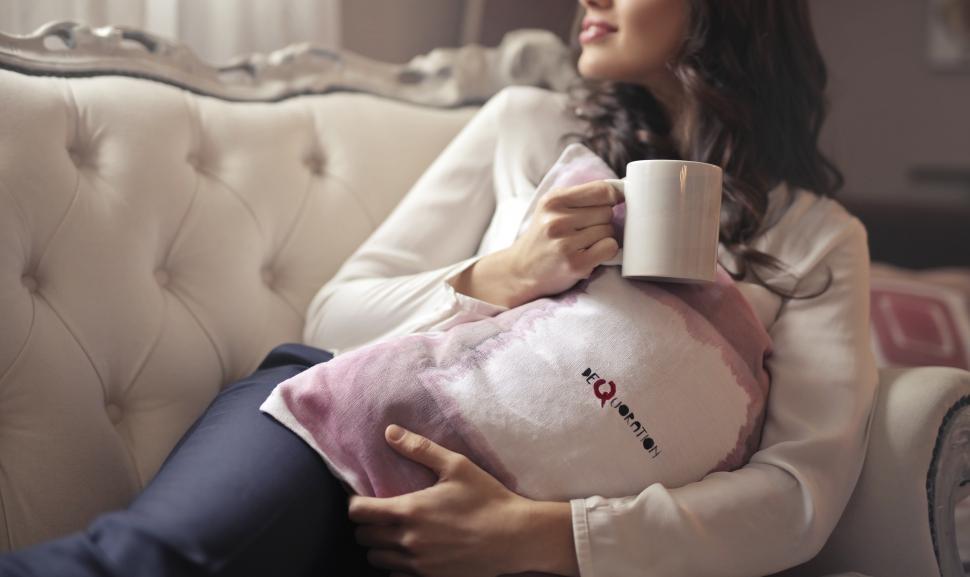 Free Image of A young brunette woman sitting on the couch holding a coffee mug 