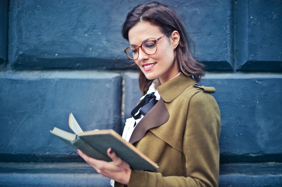 Free Image of Young Woman In Suede Pea coat Reading a Book 