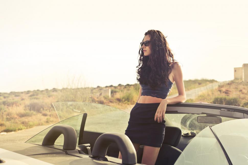 Free Image of Young Woman In Sunglasses Standing In Convertible Car 