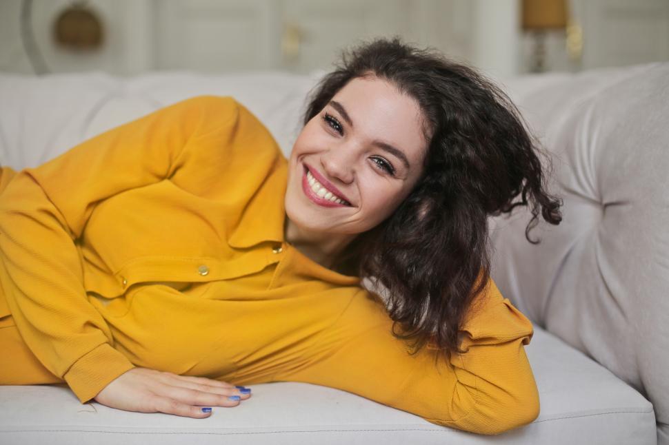 Free Image of A young woman wearing yellow button-up shirt top smiling while l 