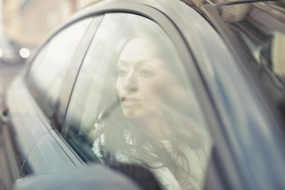 Free Image of A young woman driving a car looks outside to her right 