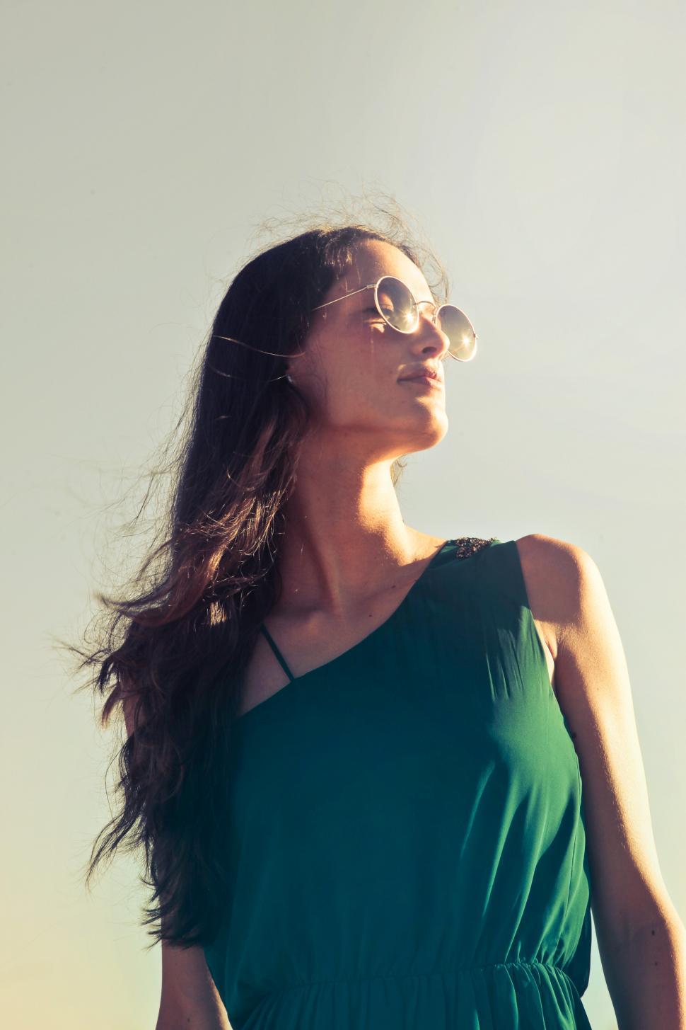 Free Image of A young brunette woman with glasses looks towards the sun 