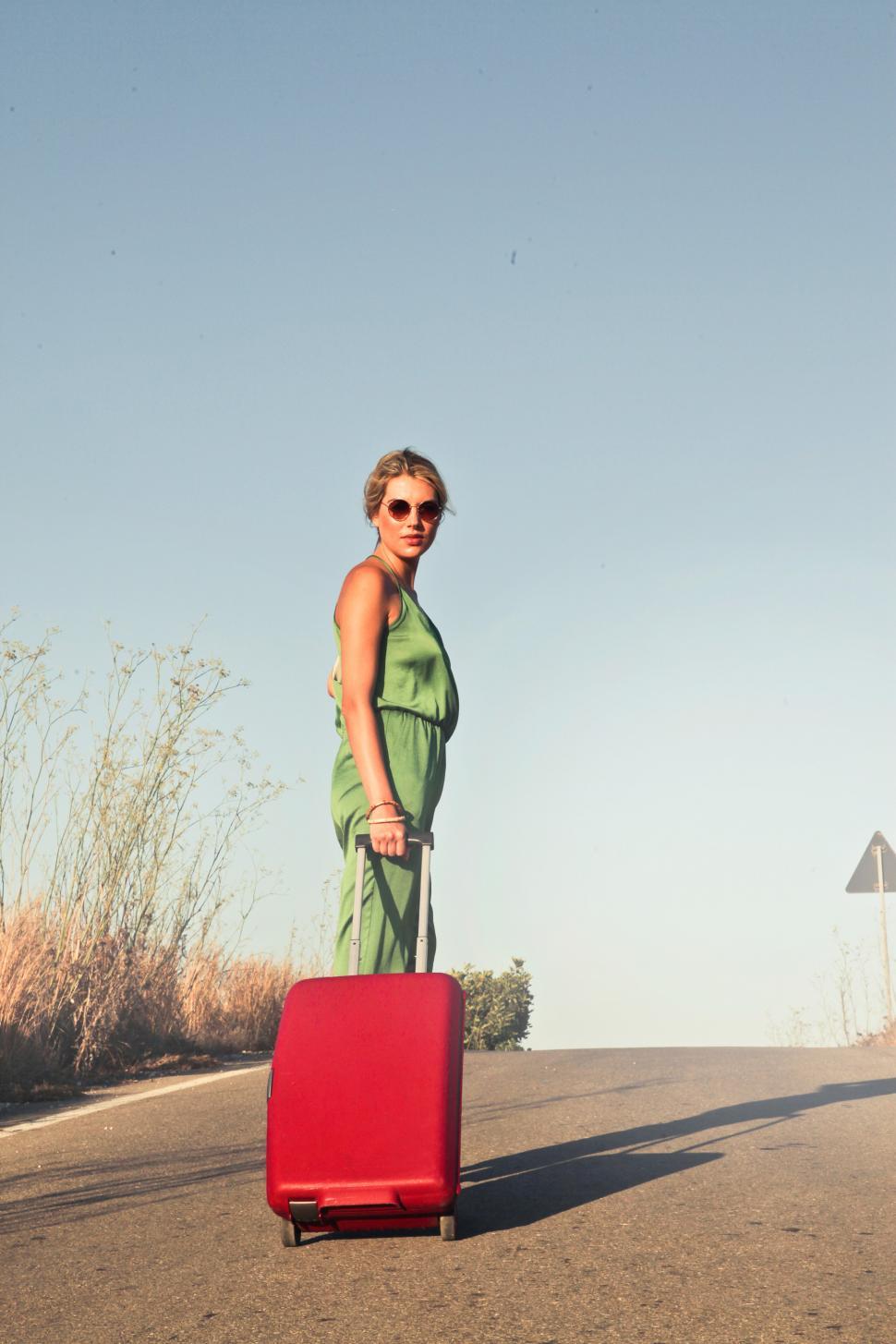 Free Image of A young blonde woman posing with red luggage trolley Bag 
