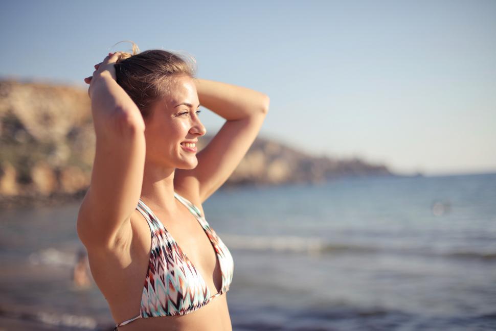 Free Image of A young blonde woman in bikini standing on the beach 