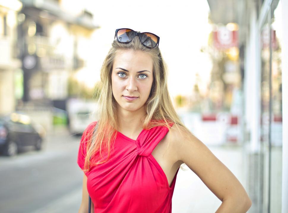 Free Image of A blonde young woman wearing red dress posing on the side walk 