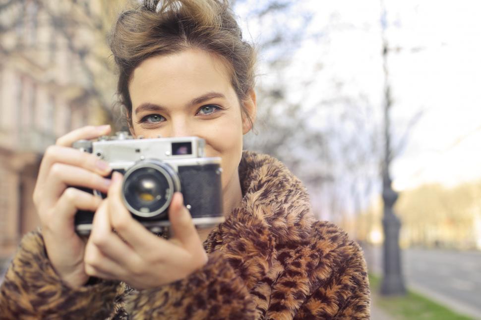Free Image of A young blonde woman posing with a vintage camera 