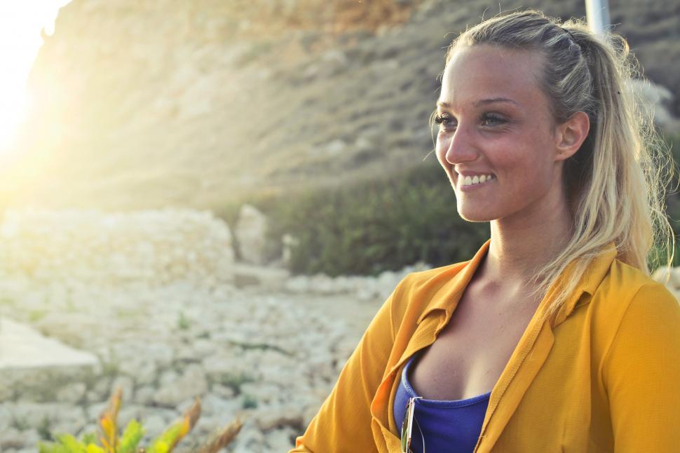 Free Image of A young blonde woman in yellow button-up shirt posing in the sun 