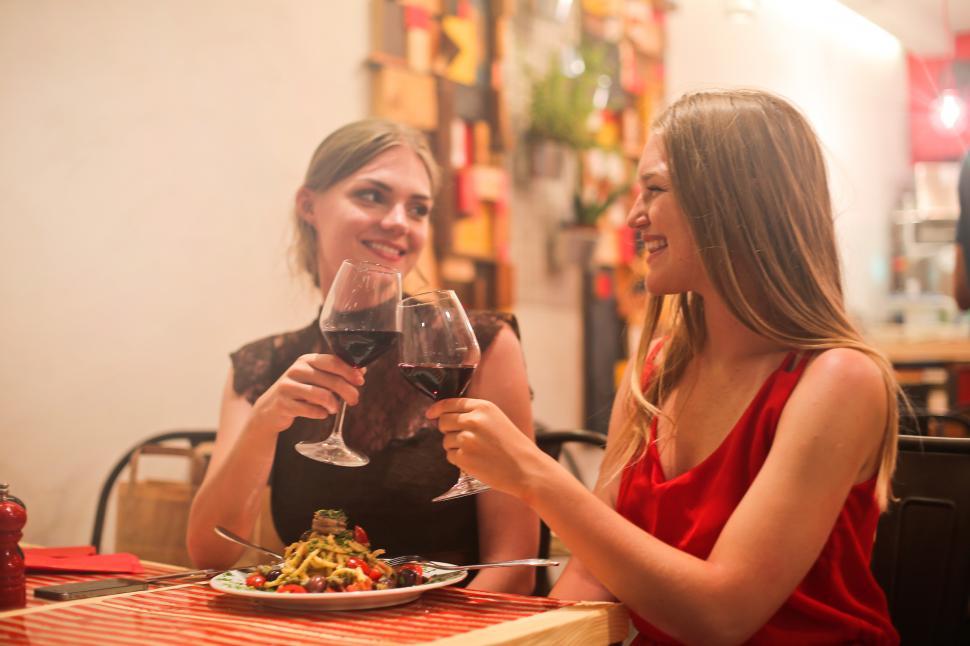 Free Image of Two young blonde women drinking red wine in a restaurant 