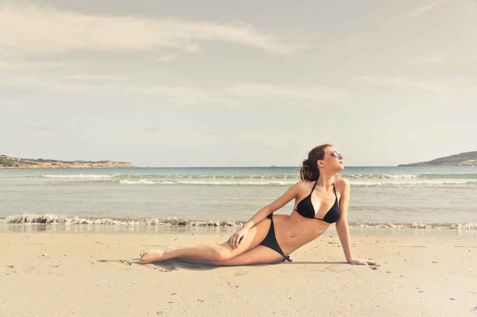 Free Image of A young brunette woman wearing black bikini posing on the beach 