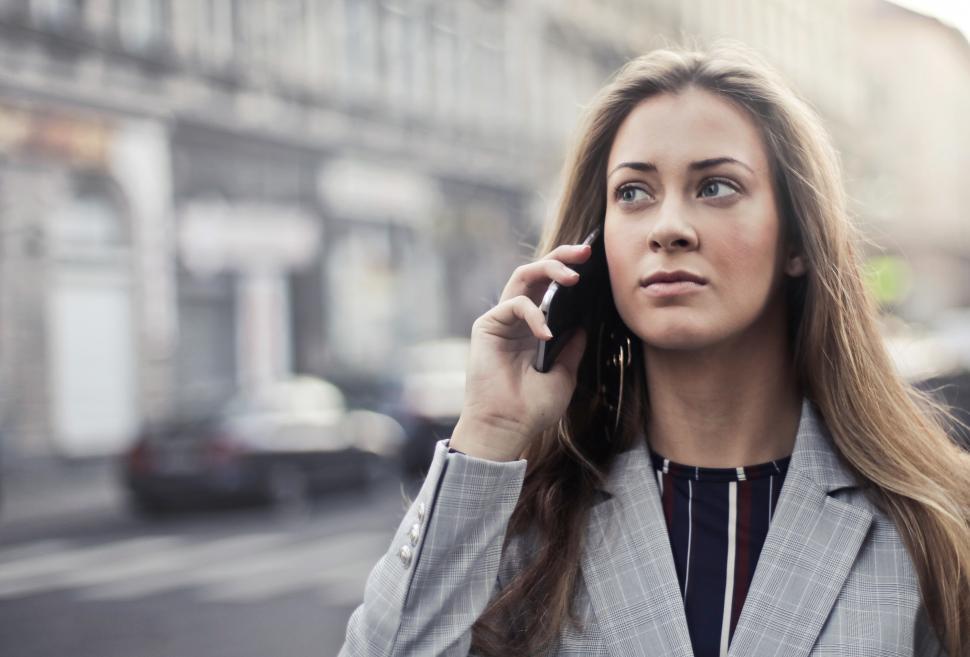 Free Image of A young blonde woman calling on her mobile in the street 