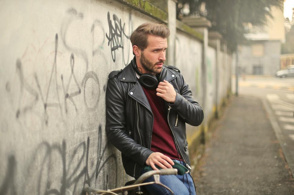Free Image of A young bearded caucasian man sitting against a wall on a bicycl 