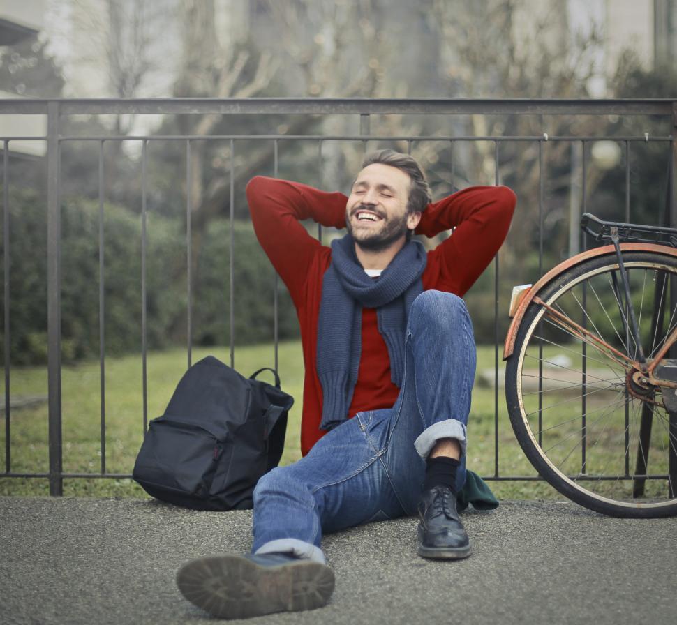 Free Image of A young bearded caucasian man sitting against metal railings wit 