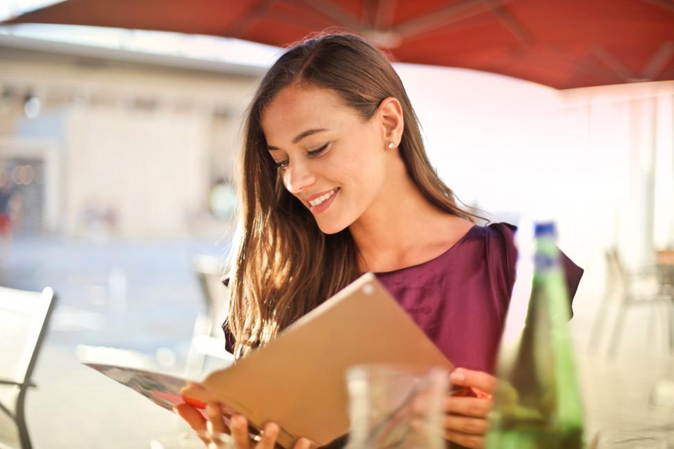 Free Image of A young blonde woman looking at a restaurant menu 