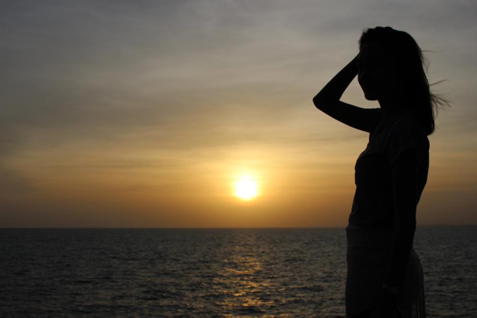 Free Image of Silhouette of the profile of a slim young woman by the sea at sunset  