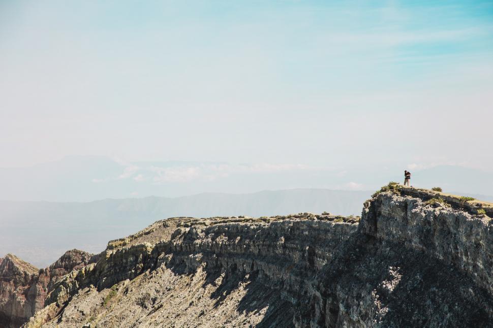Free Image of A hiker with camera on rocky edge 