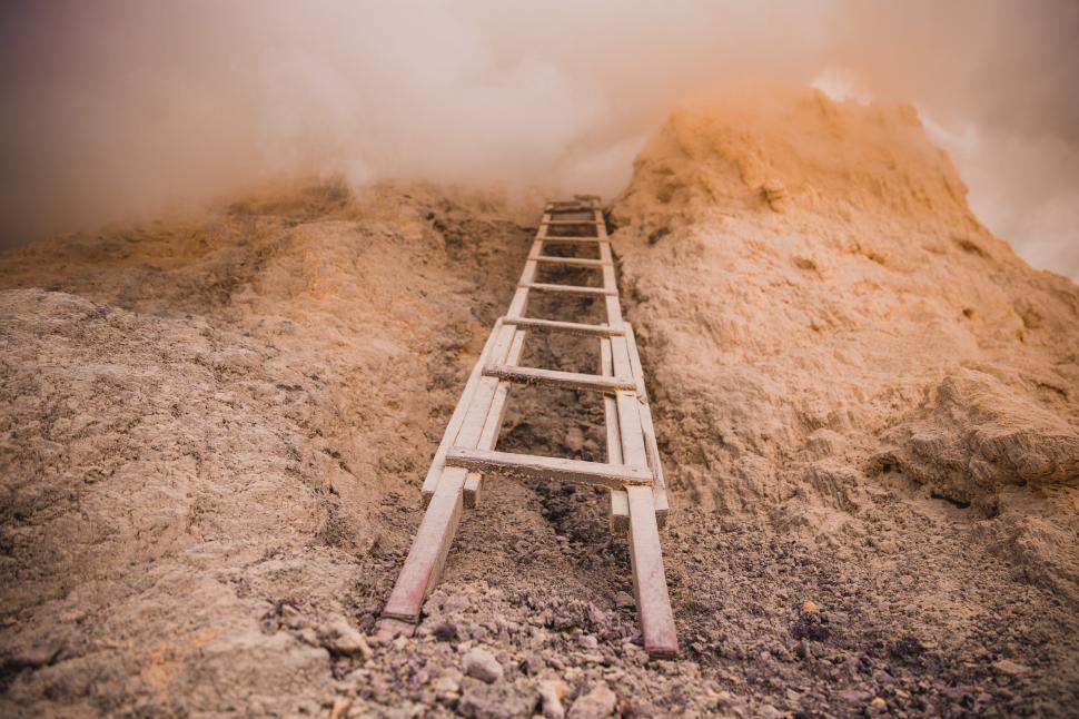 Free Image of A wooden ladder placed against a rock covered with clouds 