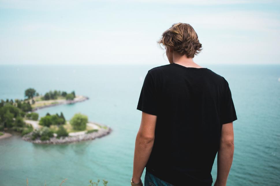 Free Image of A young caucasian man looks at the ocean 
