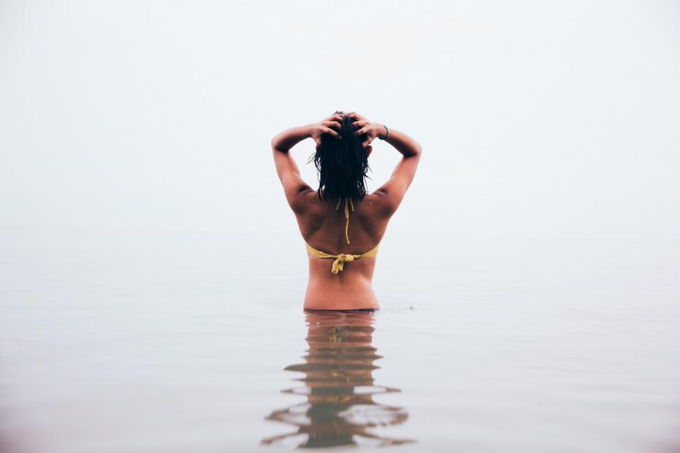 Free Image of A young woman in bikini standing in still water 