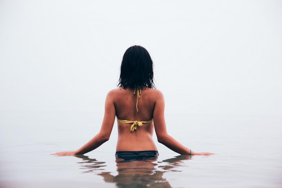 Free Image of A young woman in bikini standing in still water 