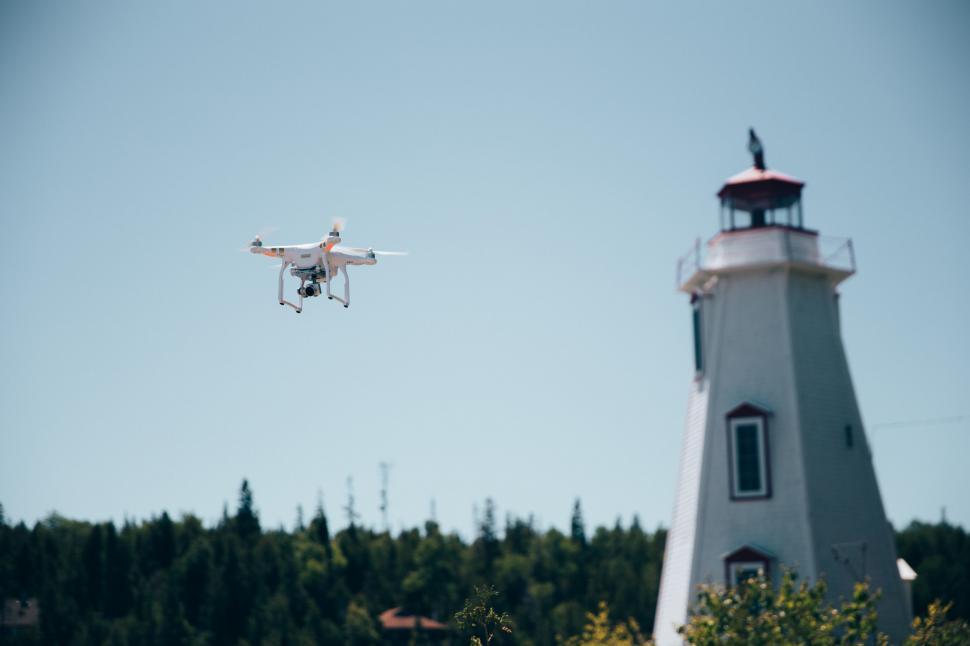 Free Image of A drone in flight near a lighthouse 