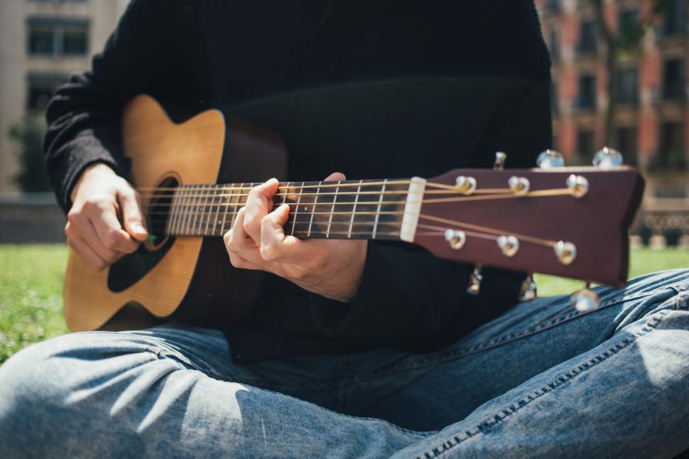 Free Image of A young man playing guitar in the park 