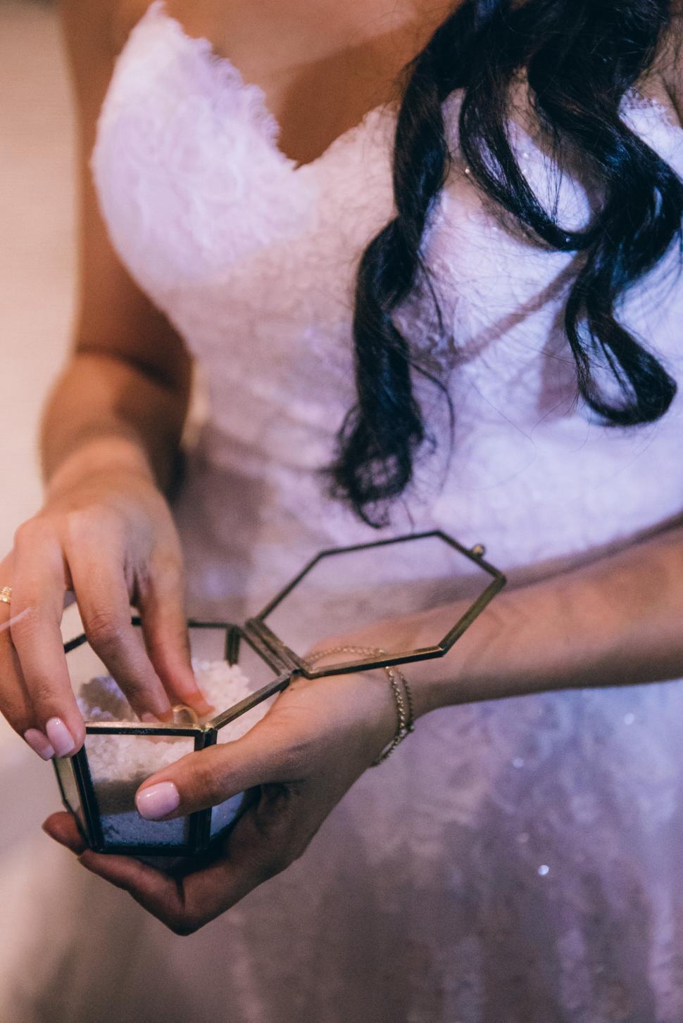 Free Image of Bride taking wedding ring out of the glass box 