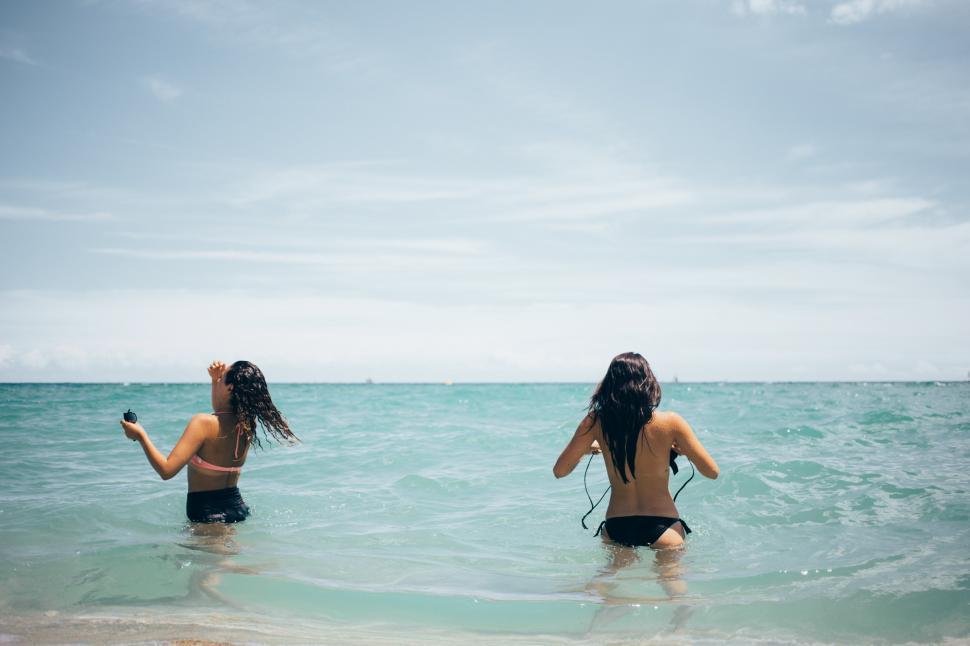 Free Image of Two caucasian women walking in the ocean waves 