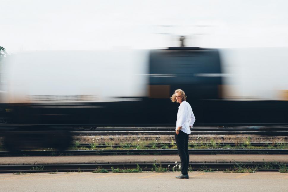 Free Image of A young caucasian man standing near passing train 