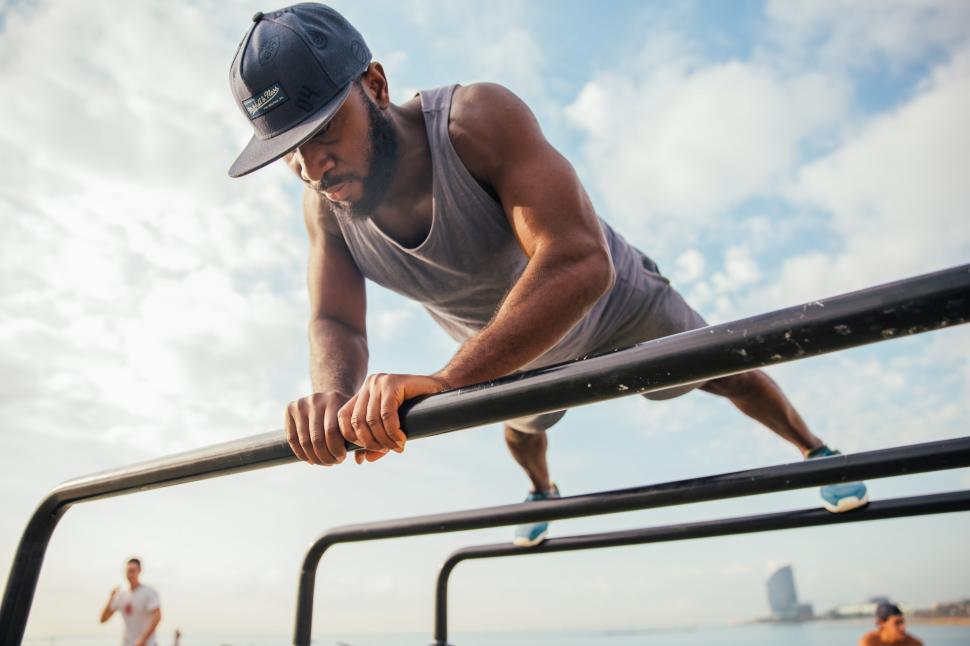 Free Image of A young African man doing push-ups on bars 
