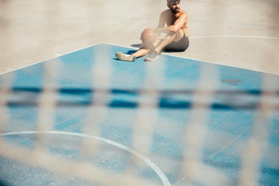 Free Image of A young man sitting on basketball court 