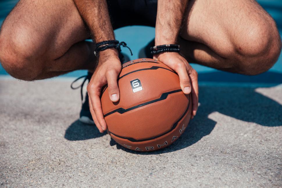 Free Image of A young player holding a basketball on the ground 