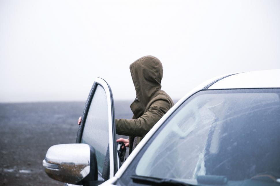 Free Image of Hiker in a hooded jacket coming out of car 