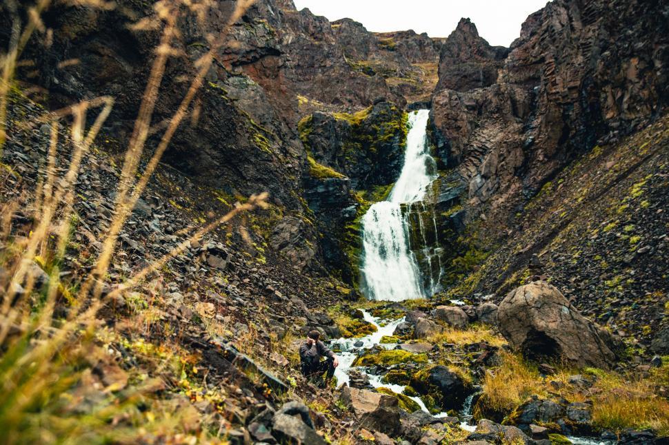 Free Image of A hiker resting by the glacier waterfall 