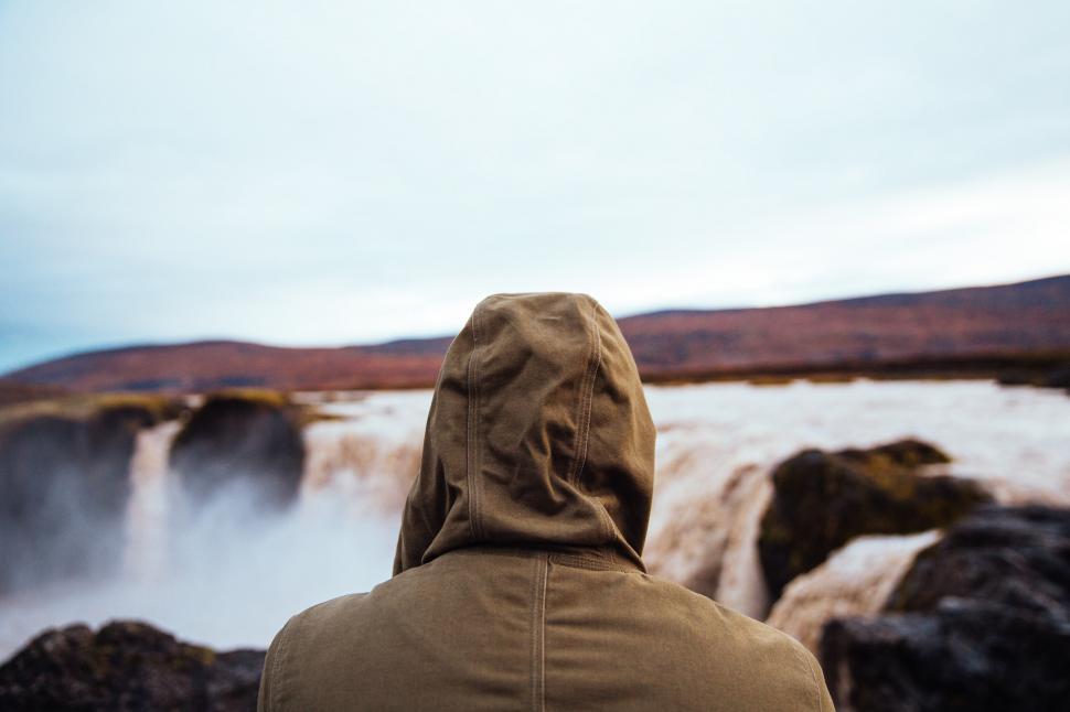 Free Image of Hiker in a hooded jacket watching the waterfall 