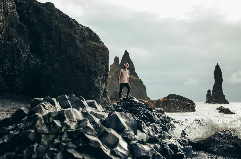 Free Image of A young caucasian hiker on volcanic rocks by the sea 