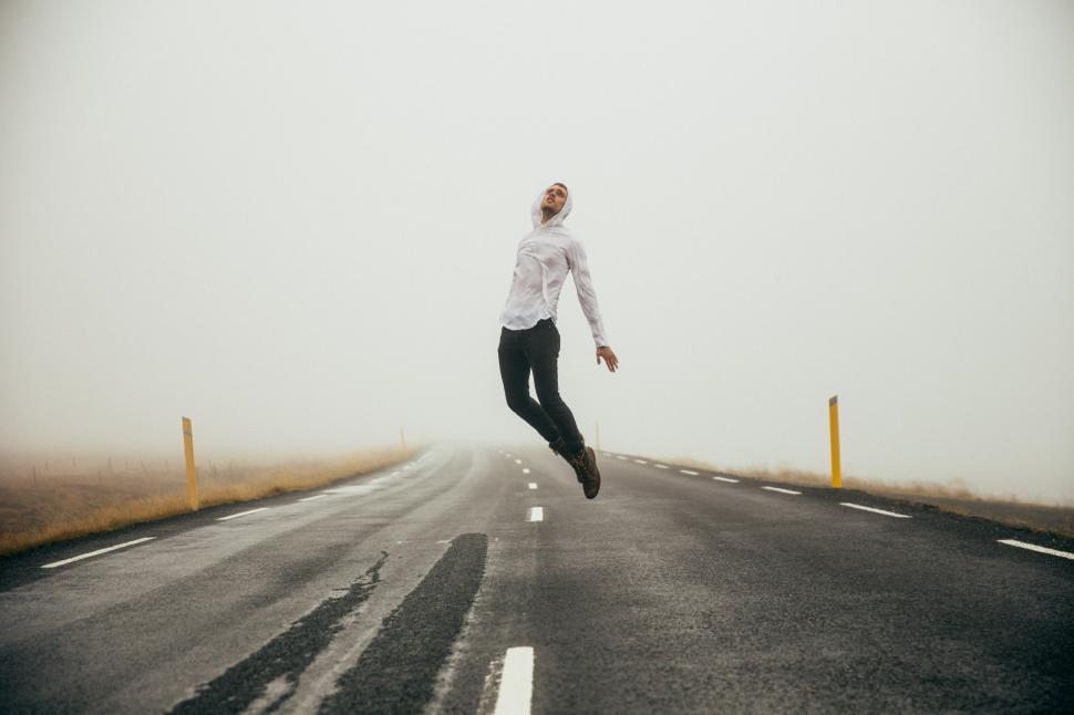 Free Image of A young caucasian man jumps on the empty highway 