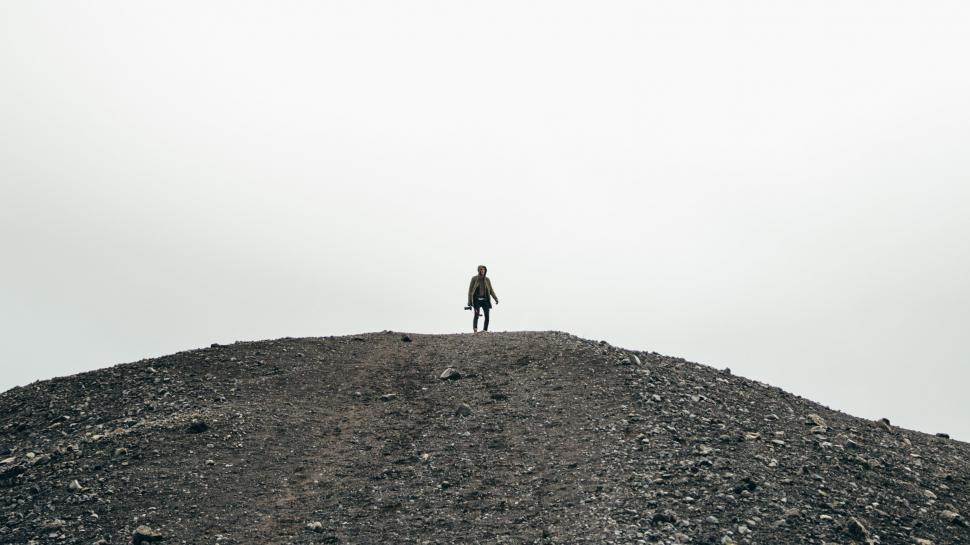 Free Image of A hiker in standing on a gravel hill 