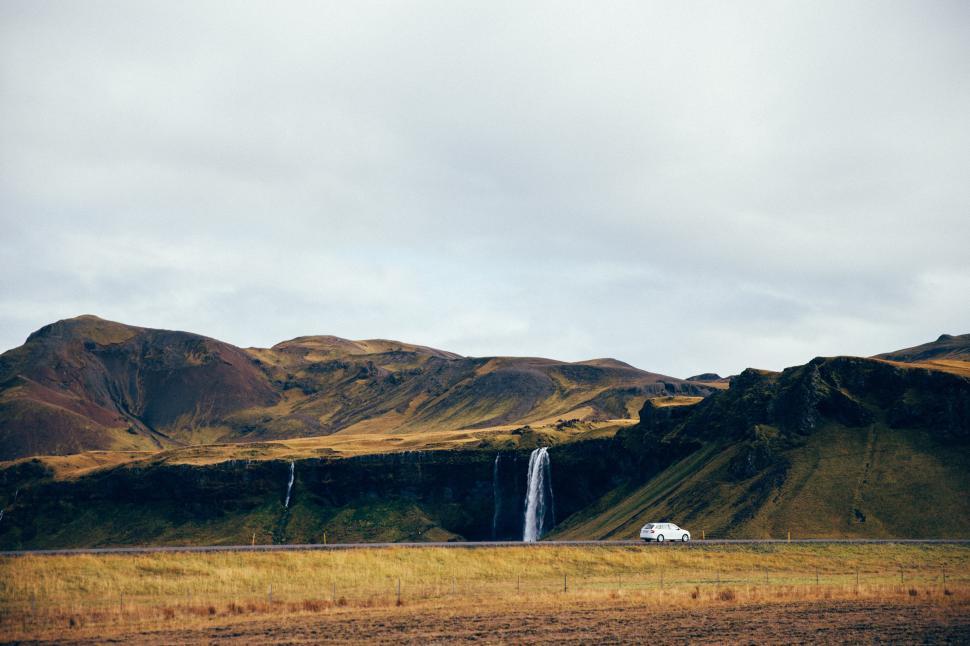 Free Image of Waterfall on green hills near a highway 