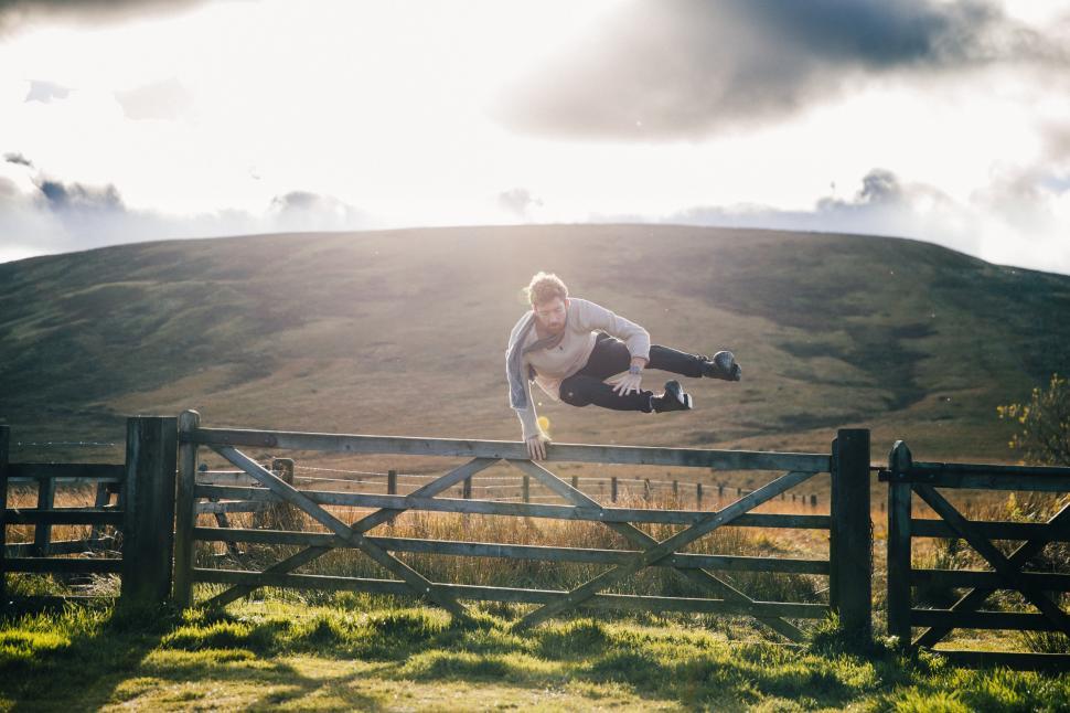 Free Image of A young caucasian man jumps over fence 