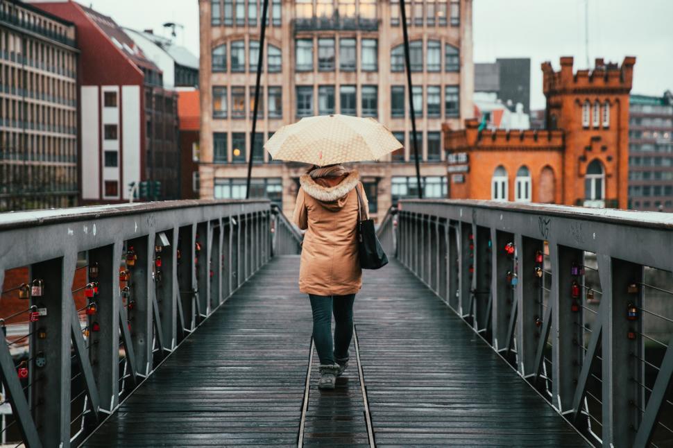 Free Image of A woman holding umbrella walking on the bridge 