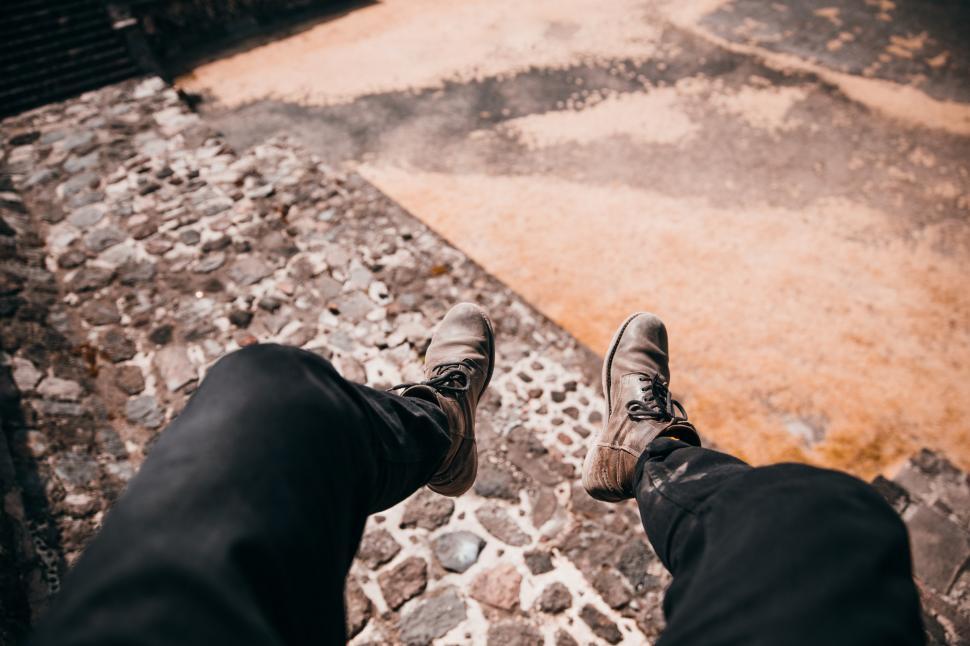 Free Image of Feet dangling over cobblestone road 