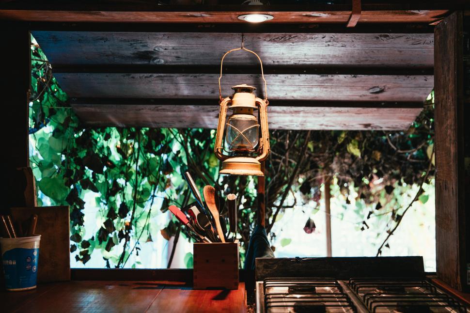 Free Image of A lantern hung on a forest hut kitchen window 