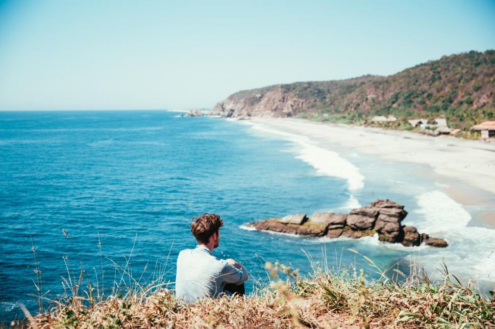 Free Image of A young caucasian man watching the beach from the top 