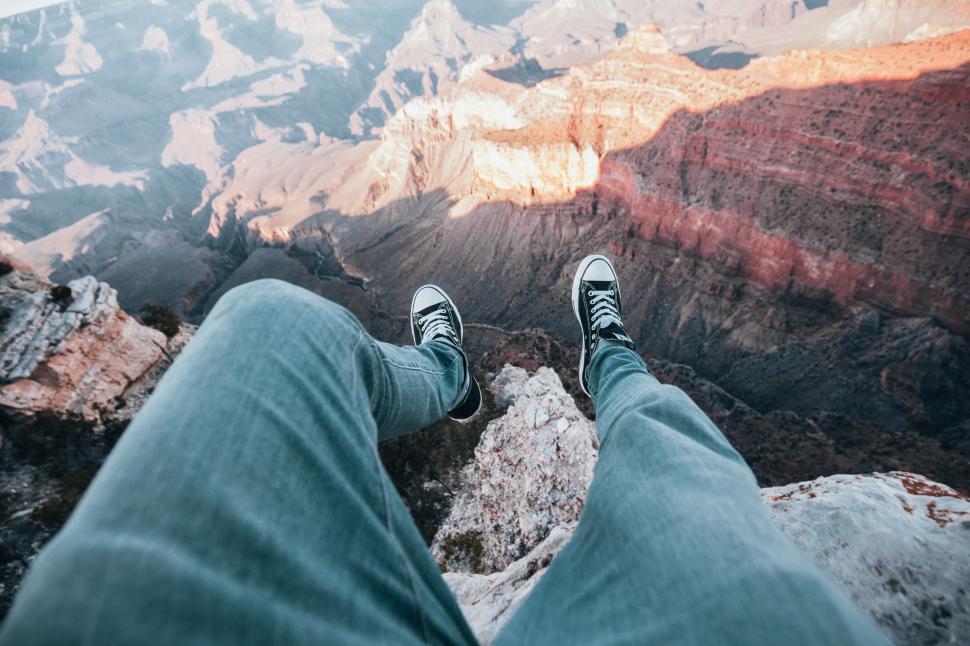 Free Image of Adventurer s legs dangled over canyon edge 