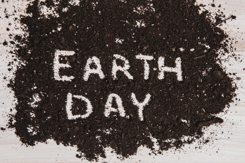 Download Free Stock Photo of The text  EARTH DAY  written out in dark soil on a white wooden surface 