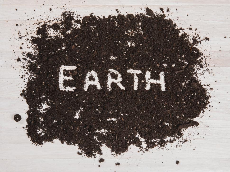 Free Image of The text  EARTH  written out in dark soil on a white wooden surface 