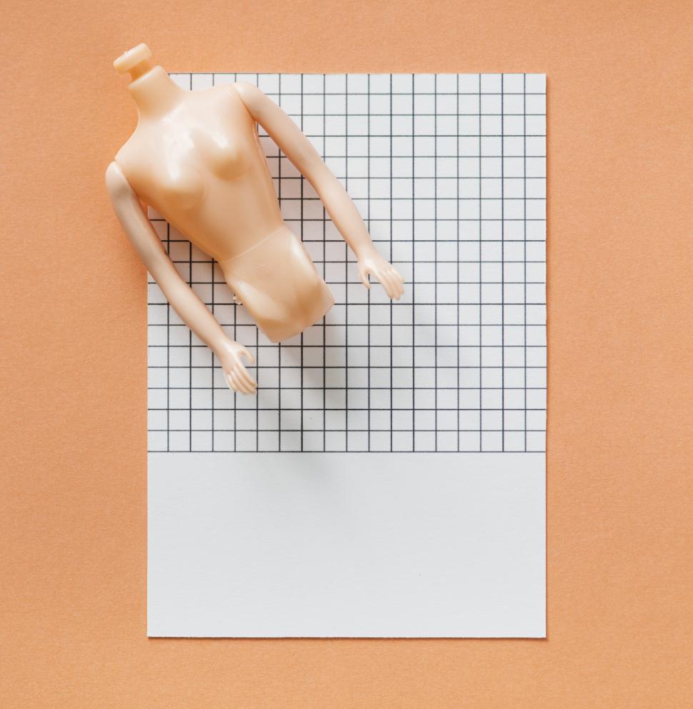 Free Image of Close up of a miniature mannequin on a paper with black grid lin 