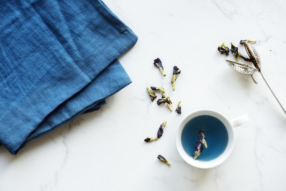 Free Image of Flat lay of a cup filled with butterfly-pea tea and a blue linen 