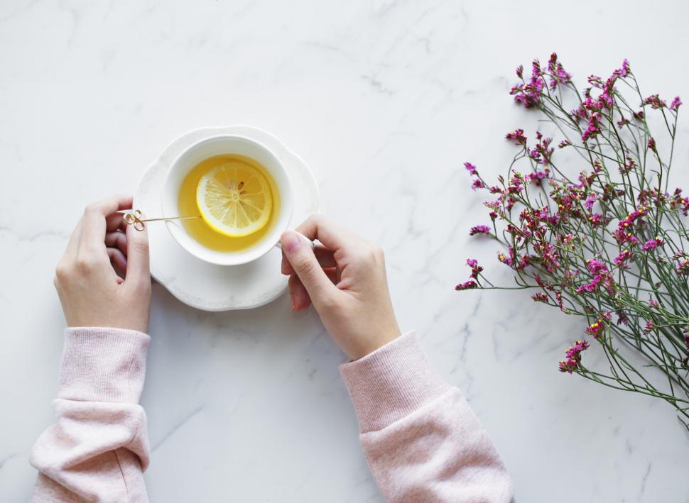 Free Image of Flat lay of hands holding a lemon tea cup and on saucer 
