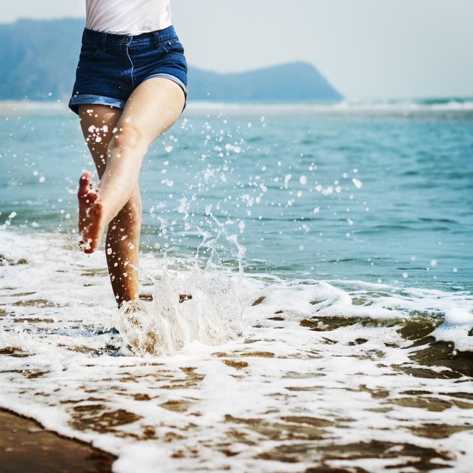 Free Image of A young woman s legs splashing water on the beach 